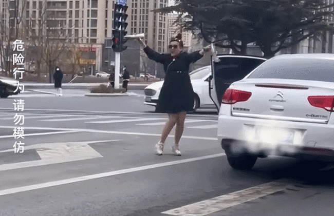 女子在路口拿高跟鞋跳舞