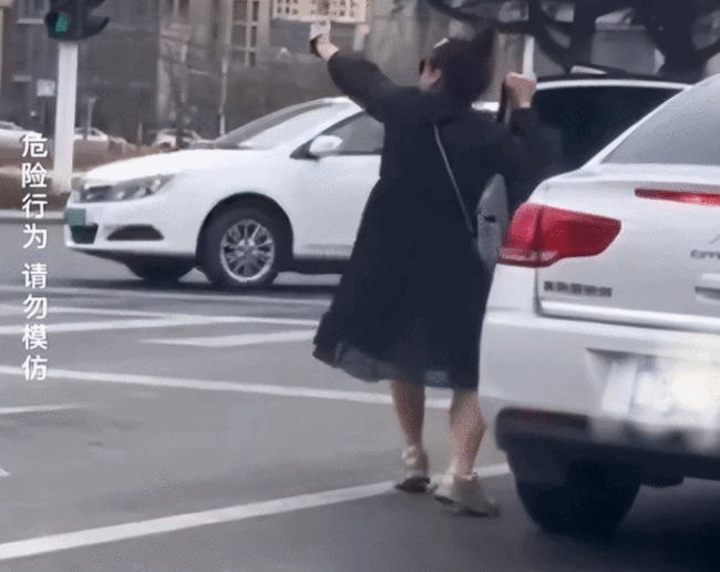 女子在路口拿高跟鞋跳舞